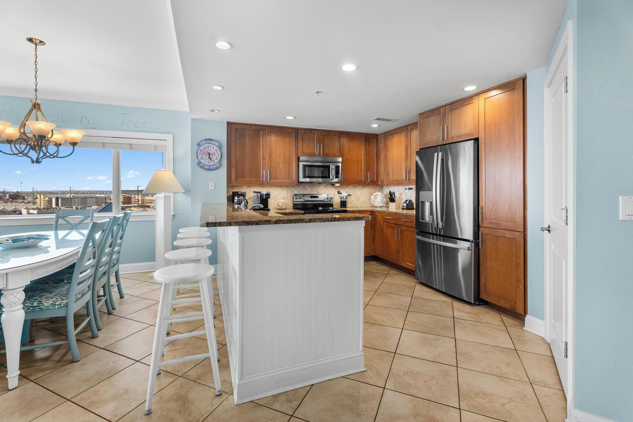 A kitchen with wooden cabinets, stainless steel appliances, a bar area, and a view through the window.