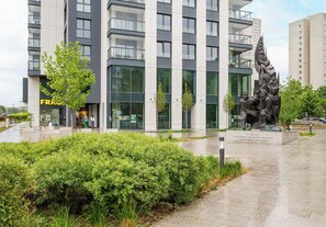 Un edificio moderno con amplios ventanales, una estatua y un jardín bien cuidado.