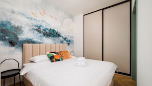 Een moderne slaapkamer met een groot bed, een wanddecoratie, een stoel en een schuifdeur.