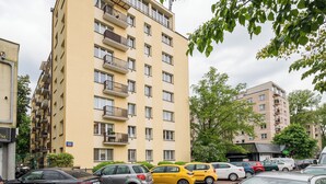 A multi-story residential building with balconies, parked cars, and a visible street sign. - Aleja Waszyngtona Sowinski Apartment (Warszawa)