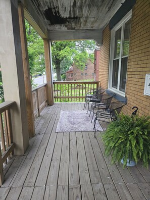A wooden porch with a view of a brick building and a tree. - Perfect 5-bedroom house in Pittsburgh for your next getaway (Pittsburgh)