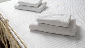 A neatly made bed with white linens and folded towels. - Żerań Brick Loft Apartment (Warszawa)