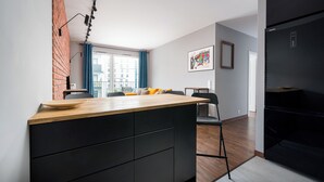 A modern kitchen with a wooden countertop, black cabinetry, and a brick accent wall. - Żerań Brick Loft Apartment (Warszawa)