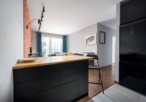 Una cocina moderna con encimera de madera, muebles negros y una pared de ladrillo decorativa.