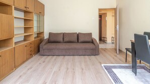 A modern living room with a sofa, wooden shelving, and a dining area. - Chorzów Comfort Apartment (Chorzów)