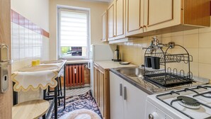 A compact kitchen with a stove, sink, and window. - Chorzów Comfort Apartment (Chorzów)