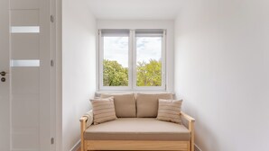 Quarto com assento junto à janela, porta e vista para árvores.