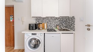 Uma cozinha compacta com máquina de lavar, cafeteira e micro-ondas.