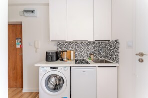 A compact kitchen with a washing machine, a coffee maker, and a microwave. - Unii Lubelskiej Standard Studio (Kołobrzeg)