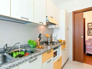 Eine Küche mit Spüle, Herd und Backofen, und einer Tür zu einem anderen Raum.
