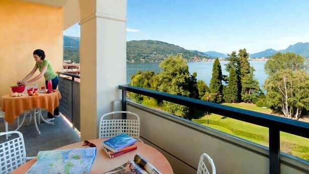Un balcon avec une table, des chaises et une personne qui prépare de la nourriture.