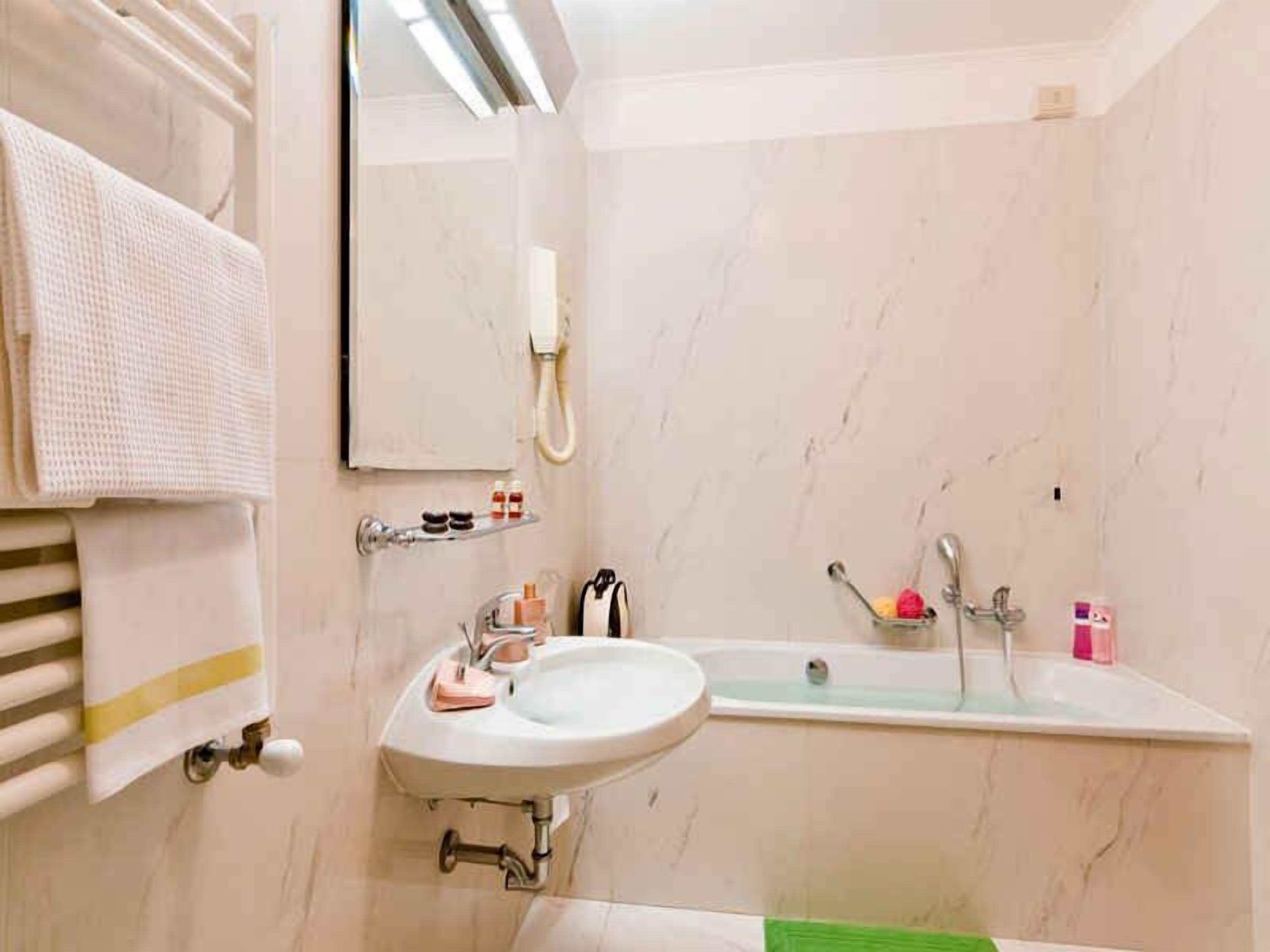Ein Badezimmer mit Waschbecken, Spiegel, Handtuchhalter und Duschbereich.