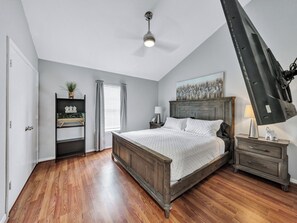 A bedroom with a wooden bed, a nightstand, a dresser, a ceiling fan, and a window with curtains. - Dallas Getaway w/ Hot Tub, Fire Pit & Detached Suite (Dallas)
