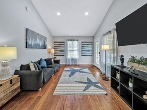 A modern living room with a sofa, a star-patterned rug, and a TV on a black stand. - Dallas Getaway w/ Hot Tub, Fire Pit & Detached Suite (Dallas)