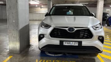 Een witte SUV geparkeerd op een bezoekersplaats in een meerlaagse parkeergarage.