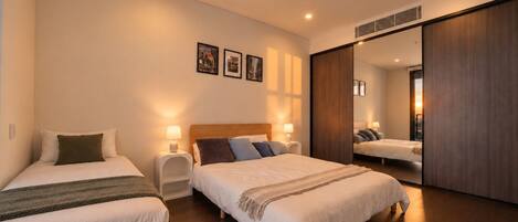 Habitación de hotel con dos camas, mesitas de noche con lámparas, un espejo grande y cuadros en la pared.