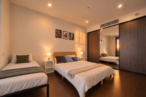 Habitación de hotel con dos camas, mesitas de noche con lámparas, un espejo grande y cuadros en la pared.