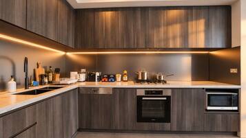 Een moderne keuken met donkere houtkasten, een ingebouwde vaatwasser, een magnetron en een gasfornuis.