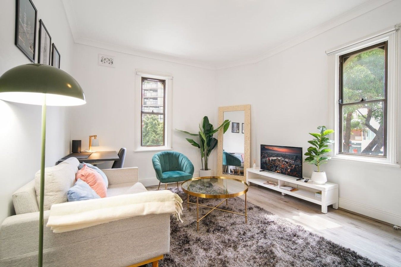 A modern living room with a sofa, a round coffee table, a television, and a large window.