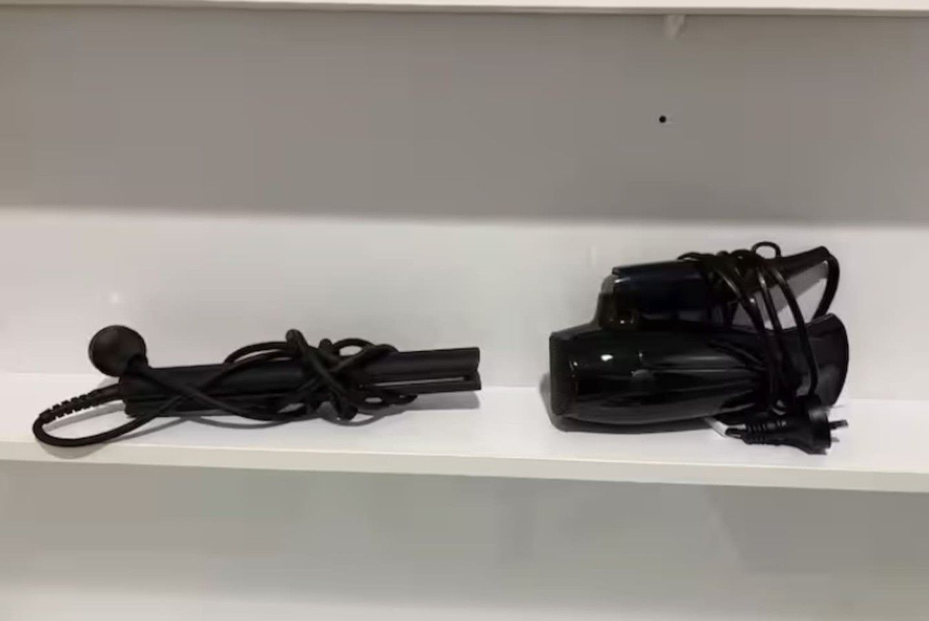 Two black electronic devices on a white shelf.
