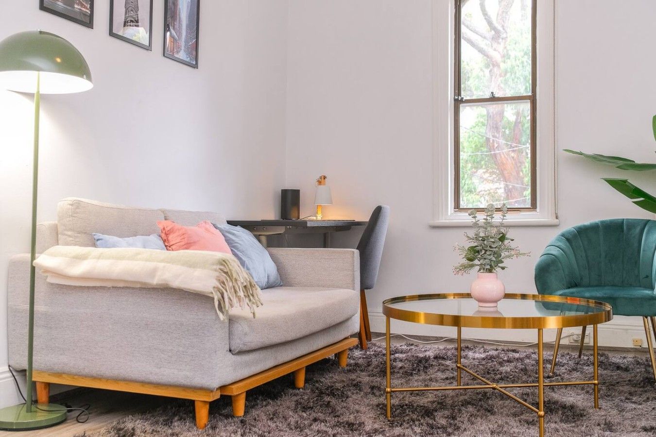 A living room with a sofa, a round coffee table, a lamp, a desk, and a chair.