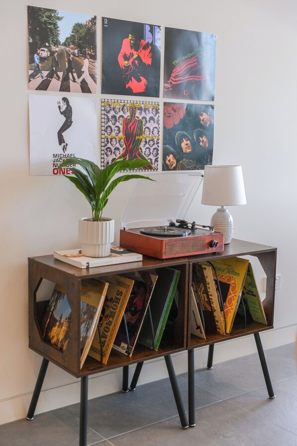 A room with a sideboard displaying vinyl records, a plant, and a lamp.
