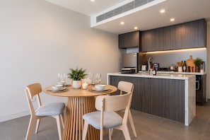 Una cocina moderna con una isla central, electrodomésticos integrados y un comedor con una mesa redonda y sillas.