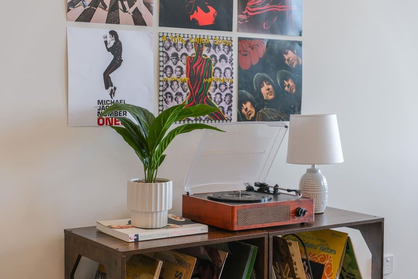 A room with a turntable, a lamp, a plant, and a book on a table.