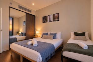 Habitación de hotel con dos camas, un espejo grande y tres cuadros en la pared.