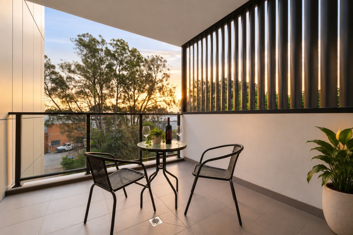 Een balkon met twee stoelen, een tafel en een bloempot.