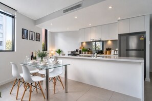 A modern kitchen with a central island, white cabinetry, and a stainless steel refrigerator.
