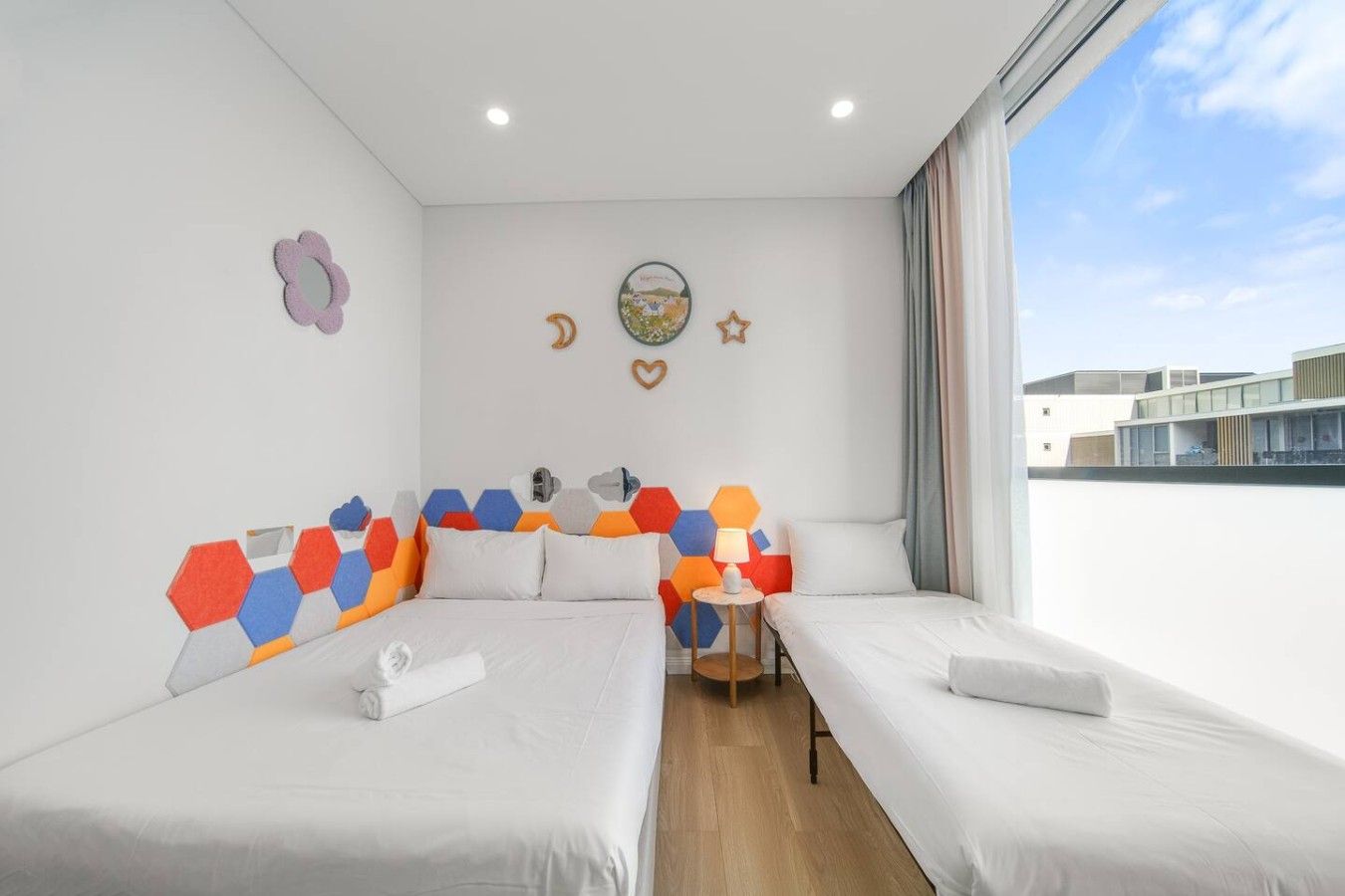 Una camera d'albergo con due letti, un tavolino e vista sulla città.