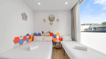 Habitación de hotel con dos camas, una mesita y vistas a la ciudad.