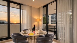 Un comedor con una mesa redonda, seis sillas y vistas a la ciudad al atardecer.