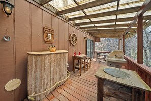 A covered outdoor deck with a wooden bar, a table with chairs, and a grill. - Lakefront luxury awaits at Beech Mountain Ski and Lake Chalet! (Beech Mountain)