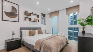 Une chambre moderne avec un grand lit, des tables de chevet, une commode et une fenêtre donnant sur un beau paysage.