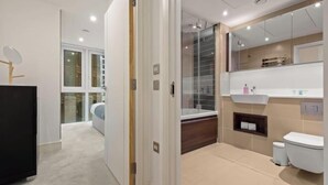 Une salle de bain moderne avec une douche à parois de verre, un lavabo blanc et des toilettes.