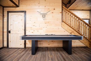 A pool table in a room with wooden walls and a wooden staircase. - Family Cabin Retreat | Hot Tub, Decks & Fire Pit (Gatlinburg)