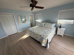A bedroom with a bed, a ceiling fan, a nightstand, and a window with blinds. - NEW Rental ~ Fish, Boat & Relax in Cudjoe Key with Ocean Access (Cudjoe Key)