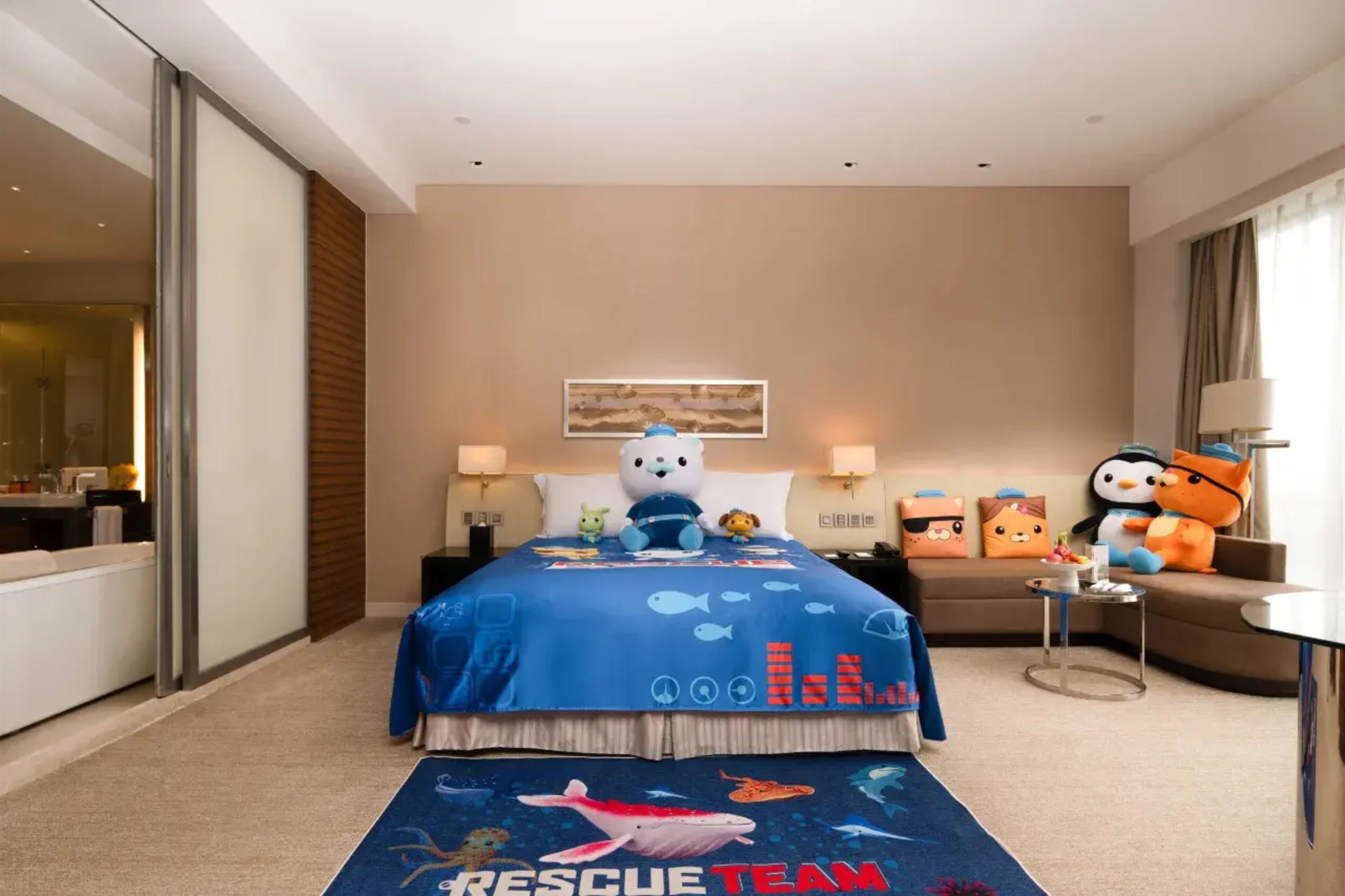 A hotel room with a bed, a sofa, a small table, and a window.