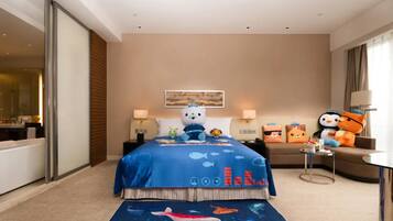 A hotel room with a bed, a sofa, a small table, and a window.