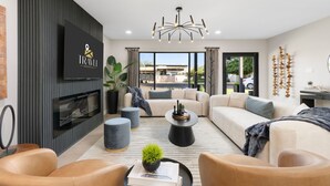 Ein modernes Wohnzimmer mit Flachbildfernseher, Kamin, Sofa und Couchtisch.