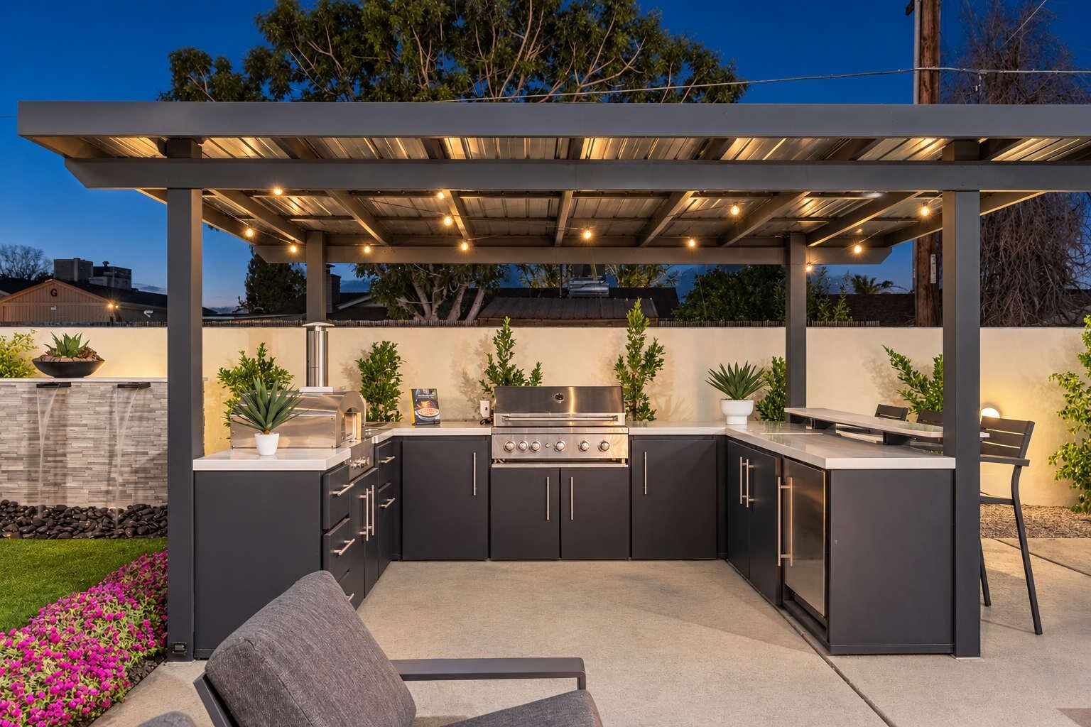 Grill burgers and steaks for everyone under this covered outdoor kitchen. A small fridge under the counter keeps the meat, sauces, and drinks cool.