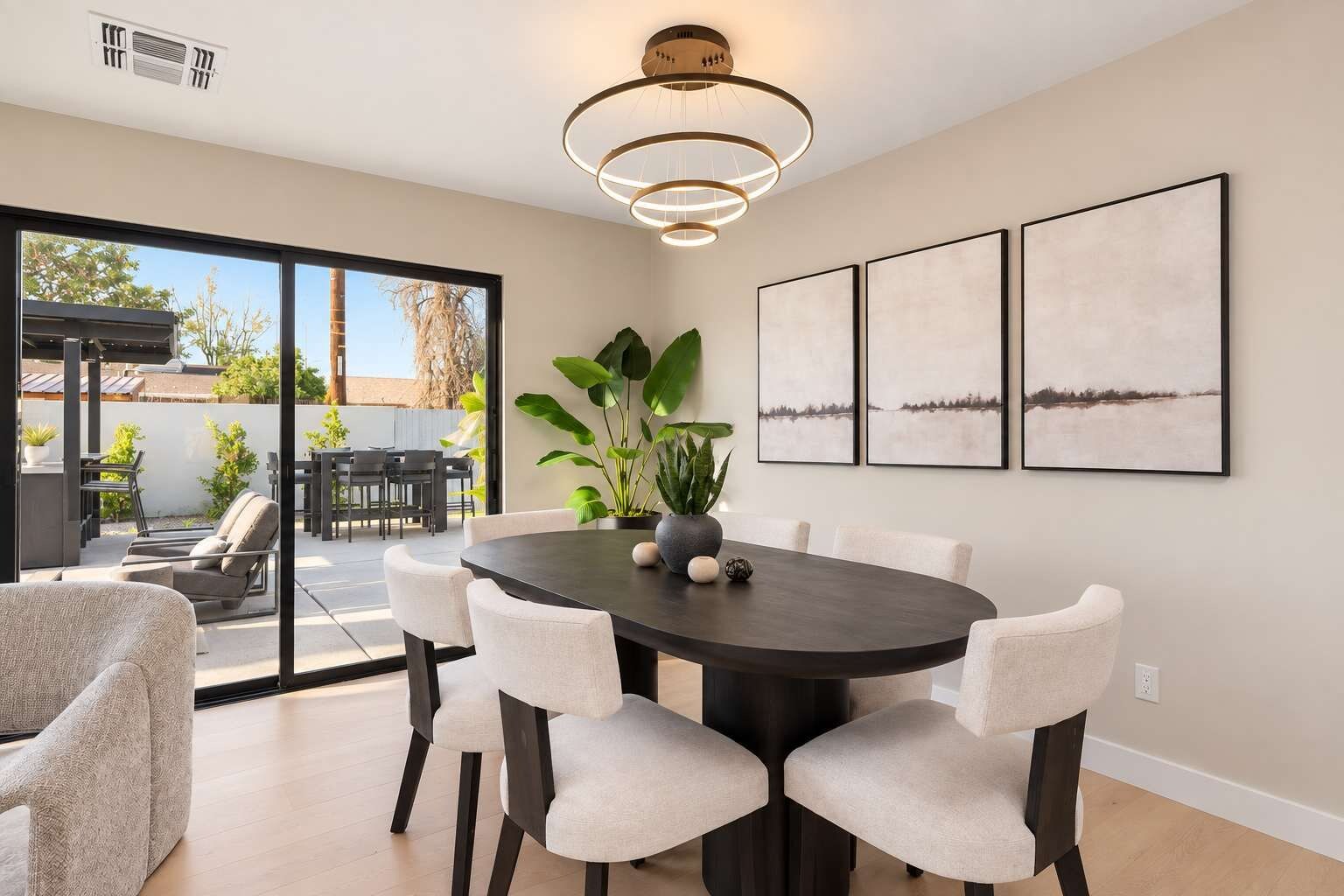 A dining area with a round table, six chairs, and a potted plant.