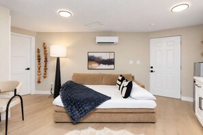 Een moderne slaapkamer met een bed, een bedlampje en een schilderij aan de muur.