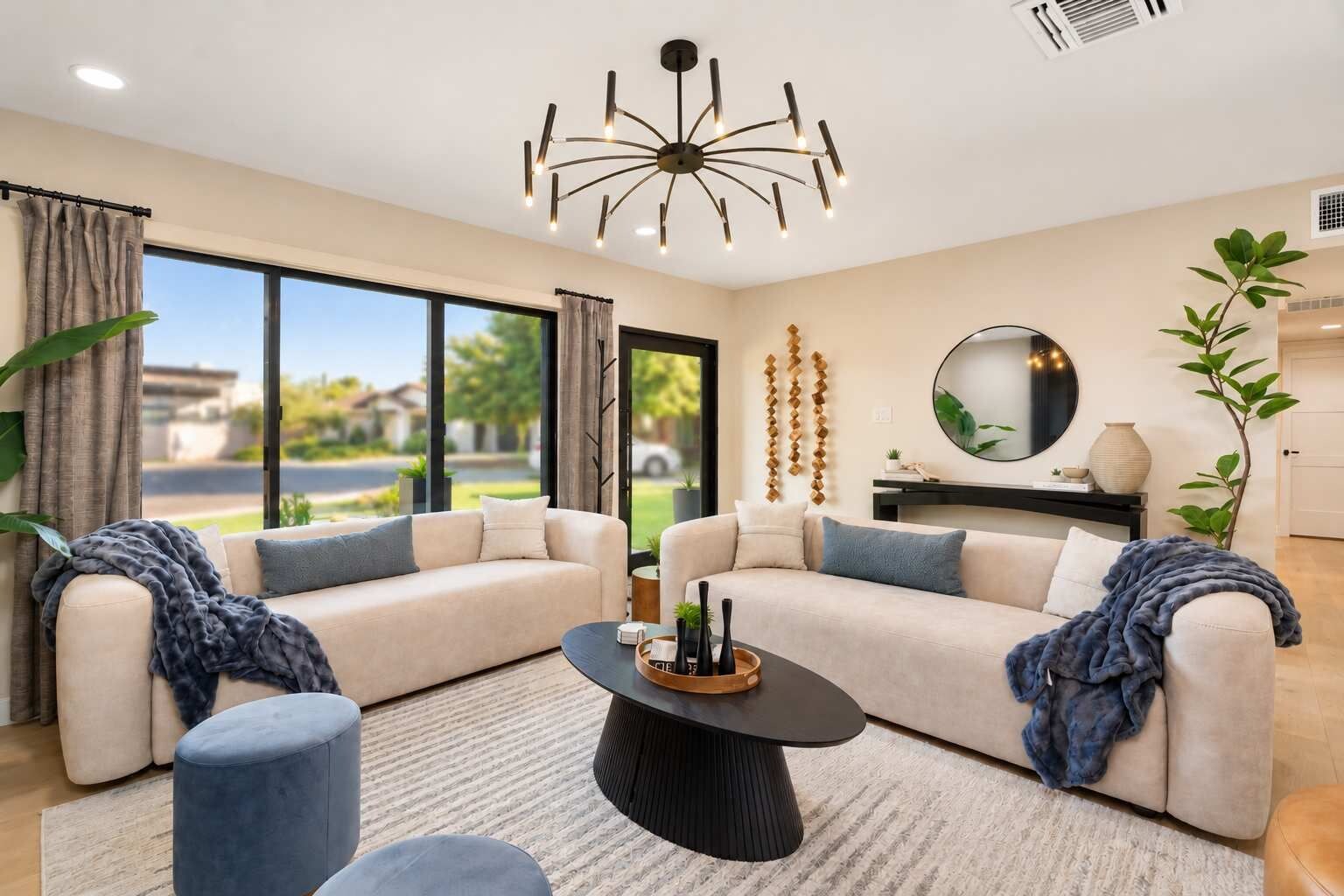 A modern living room with a sofa set, a coffee table, and a large window offering a view of the outdoors.