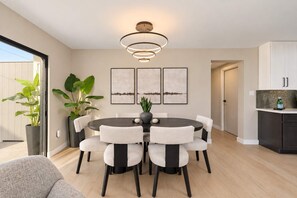 A modern dining area with a round table, six chairs, and a contemporary chandelier. - NEW | The Barrington | Old Town Designer Retreat (Scottsdale)