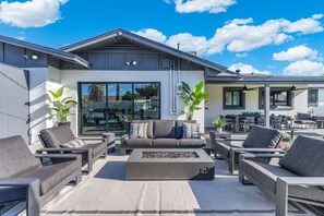 A modern outdoor living area with a sofa set, a fire pit, and potted plants. - NEW | The Barrington | Old Town Designer Retreat (Scottsdale)