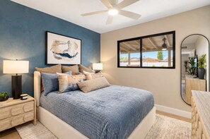 A bedroom with a bed, nightstands, a ceiling fan, a large window, and a mirror. - NEW | The Barrington | Old Town Designer Retreat (Scottsdale)