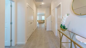 A hallway with white doors, a glass console table, and a mirror on the wall. - Value Edge (Kissimmee)